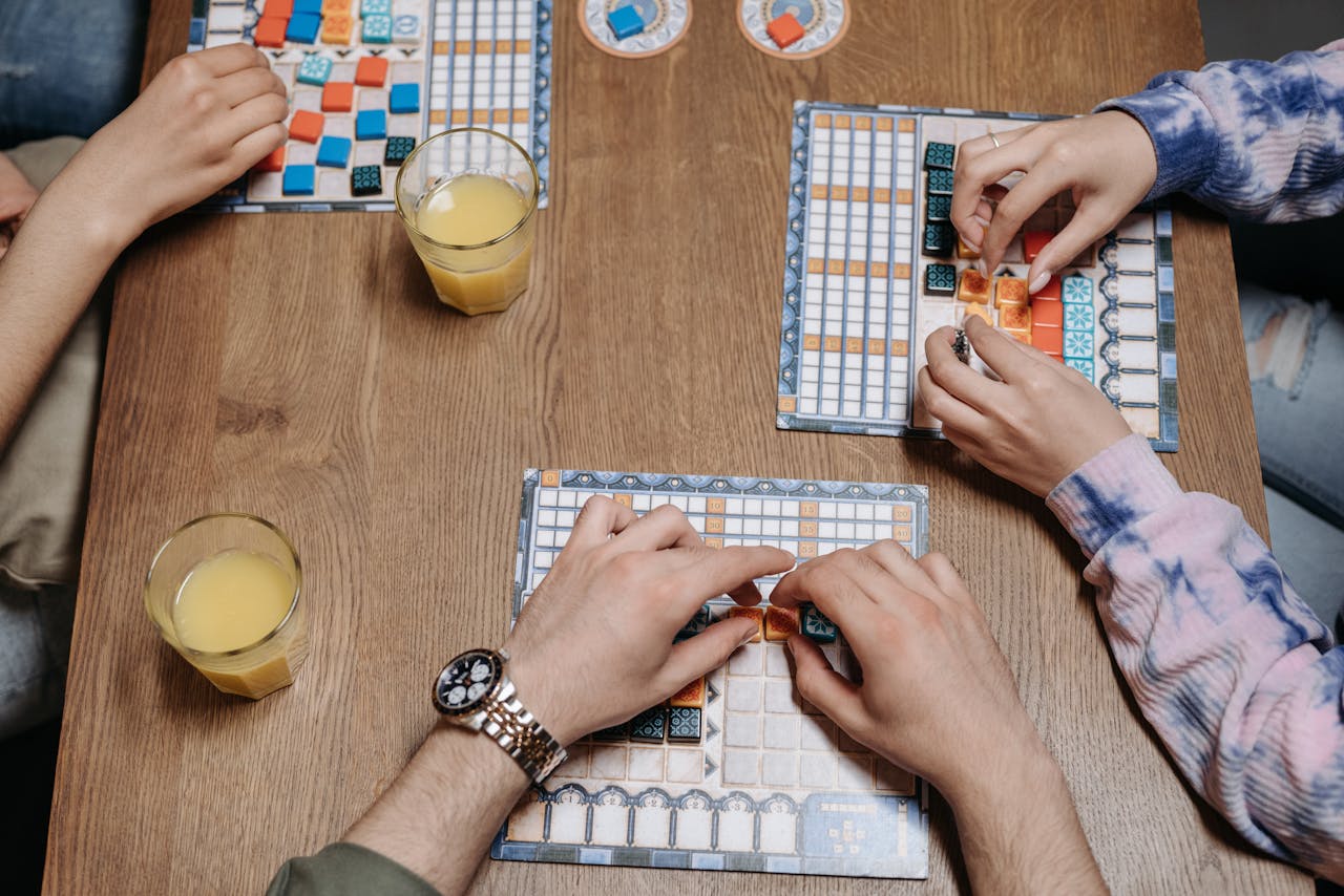 Close-up of hands and board game tiles during a fun gaming session indoors.