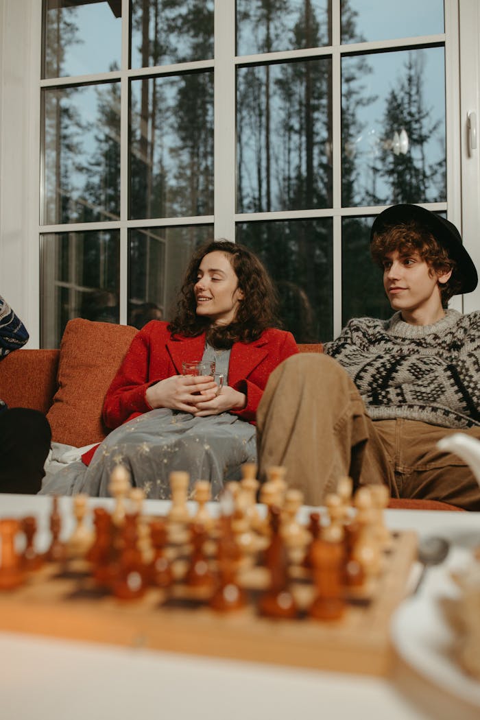 A group of young adults enjoying a cozy indoor setting with a chessboard in the foreground.